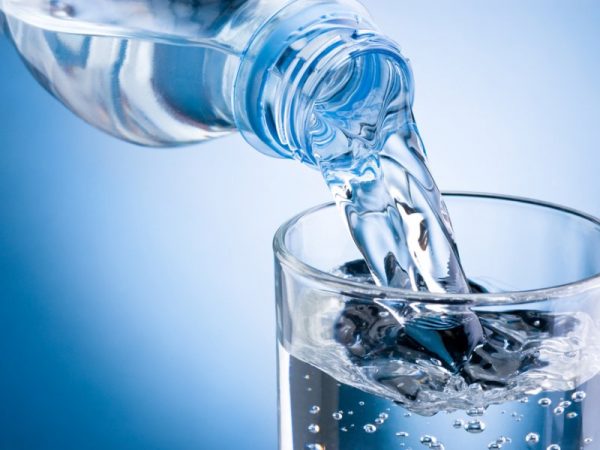 Воду из бутылки наливают в стакан